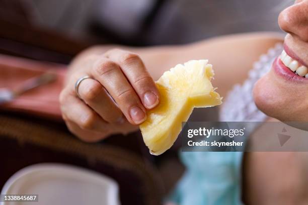 feche acima de uma mulher comendo abacaxi fresco. - abacaxi - fotografias e filmes do acervo