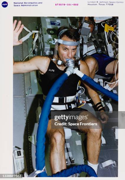 Wearing the Astronaut Function Experiment breathing hardware and instrumented vest, astronaut Richard M Linnehan sits on the ergometer in the science...