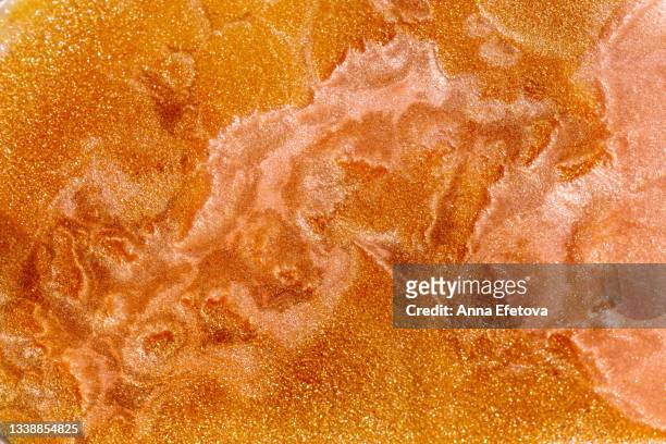 background made with texture of bronze-gold-copper shimmer oil with glittering particles for sunbathing. body lotion with sun protection factor for safe tan. macrophotography in flat lay style - skin texture stockfoto's en -beelden