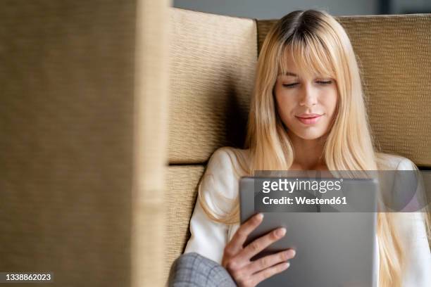 blond female professional using digital tablet at office - office sofa stock-fotos und bilder