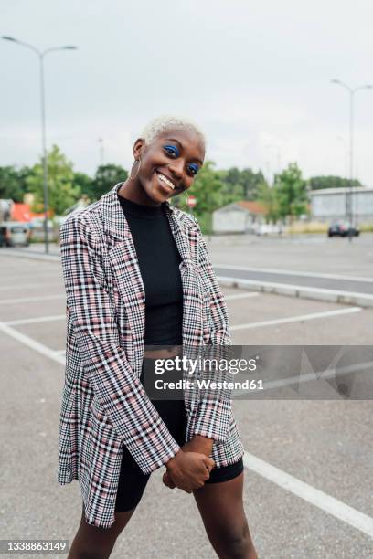 smiling young woman standing on road - woman black jacket stock pictures, royalty-free photos & images