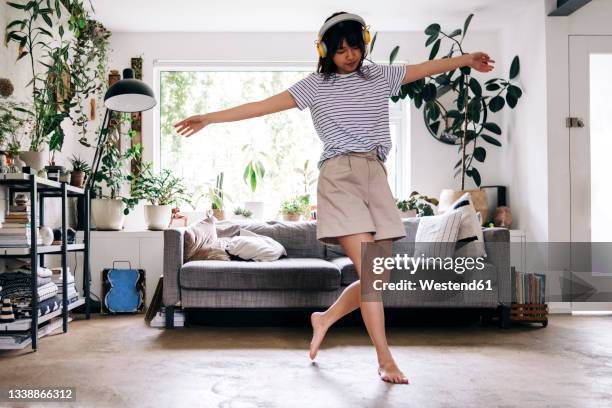 carefree woman with arms outstretched dancing at home - moving sofa stock pictures, royalty-free photos & images