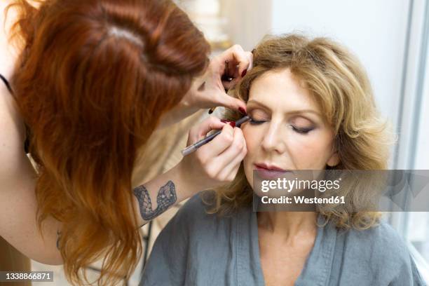 female make-up artist applying eye shadow to senior woman - old woman tattoos stock pictures, royalty-free photos & images