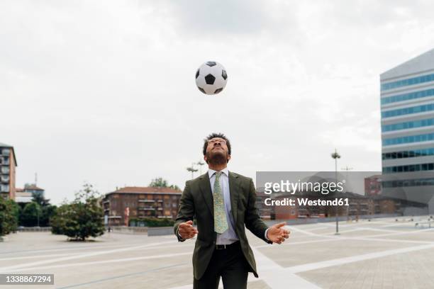 businessman heading the ball while playing in city - heading the ball stockfoto's en -beelden
