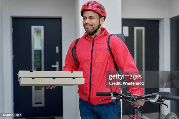 deliveryman with pizza boxes and bicycle standing in front of house door - pizza delivery stock pictures, royalty-free photos & images