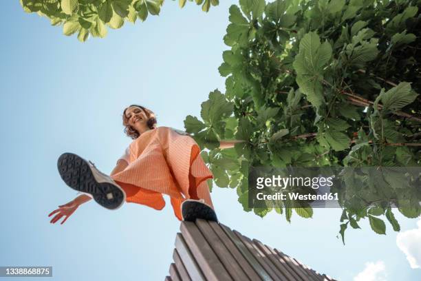 smiling woman standing on retaining wall - below stock pictures, royalty-free photos & images