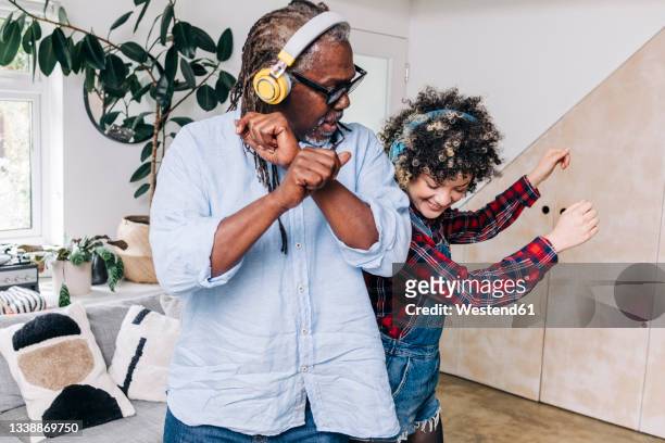 father and daughter with headphones dancing together at home - father daughter dance stock-fotos und bilder