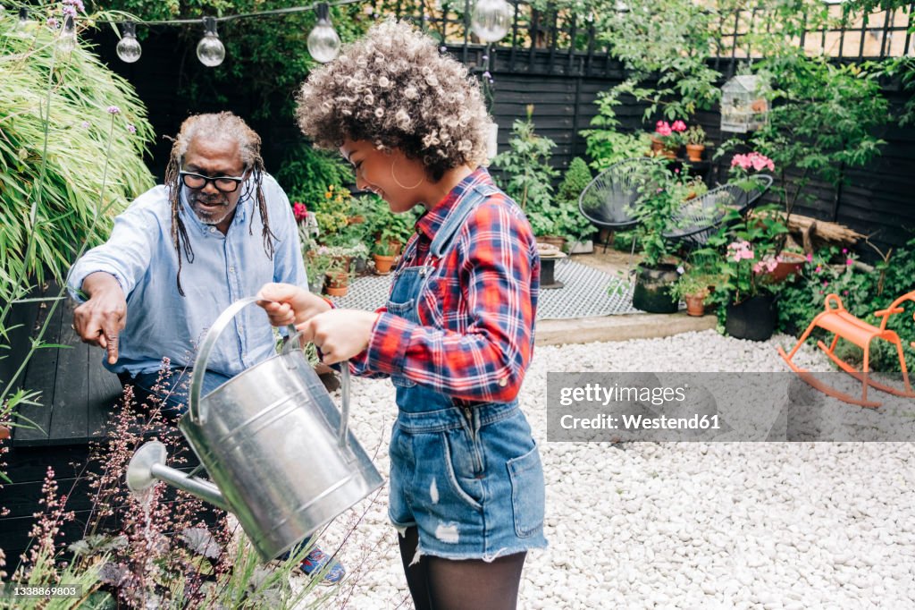 Father talking with daughter while gardening at backyard