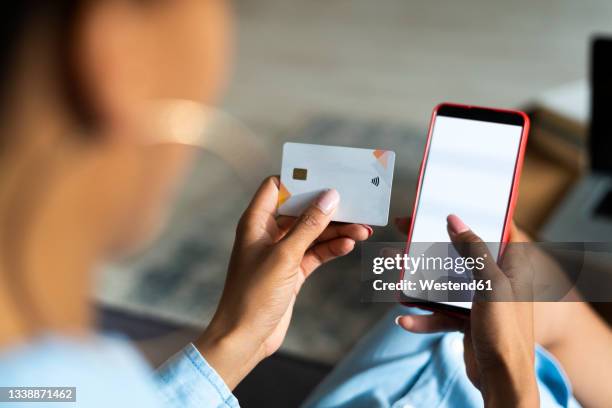 young woman doing online shopping through smart phone while paying with credit card - charging phone stock pictures, royalty-free photos & images
