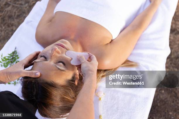 masseuse giving facial massage to customer lying on table - spooning stock pictures, royalty-free photos & images