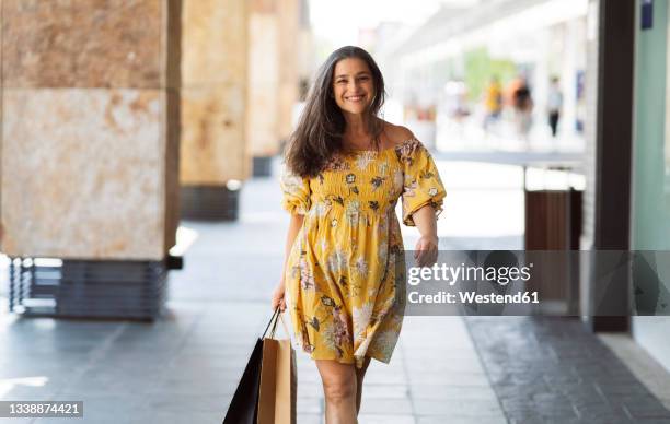 woman with shopping bags walking through arcade - yellow dress stock-fotos und bilder