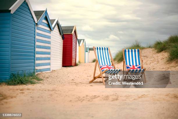 empty deck chair near huts at beach - silla de playa fotografías e imágenes de stock