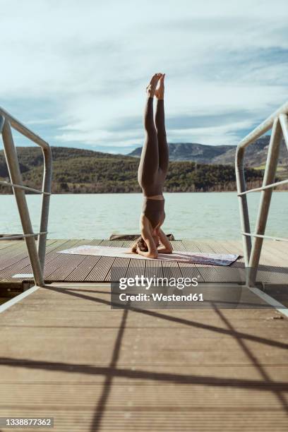 sportswoman doing sirsasana on jetty - shirshasana stock pictures, royalty-free photos & images