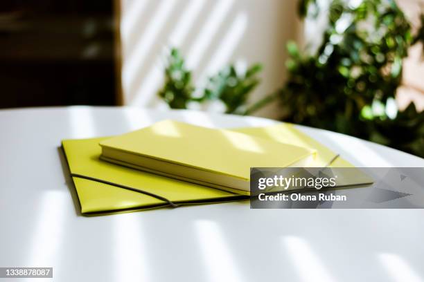 yellow folder with yellow book on white table. - yellow envelope stock pictures, royalty-free photos & images