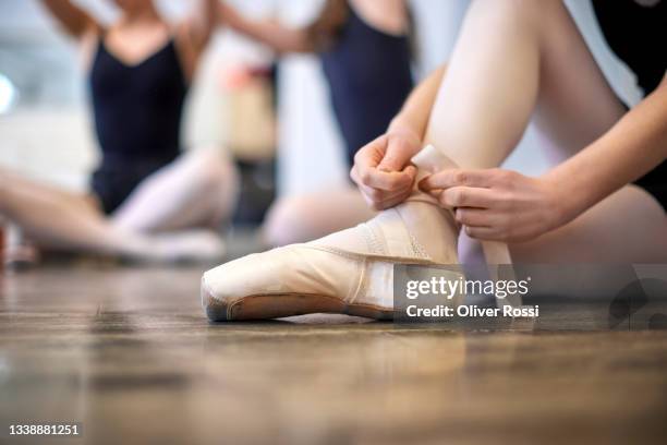 close-up of dancer sitting on the floor putting on ballet shoe - ballerina feet stockfoto's en -beelden