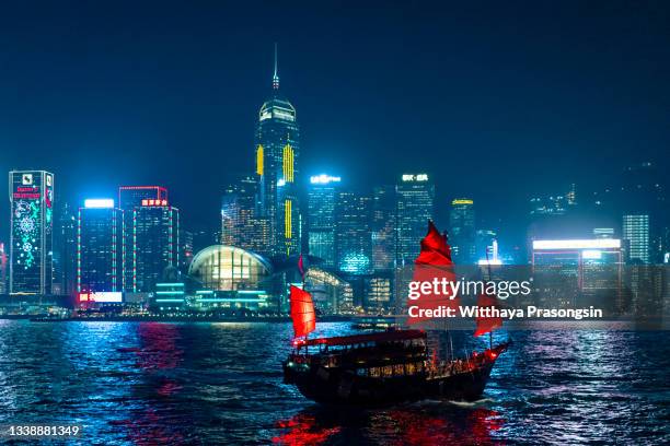 traditional junk boat sailing across victoria harbour, hong kong. - sailing ship night stock pictures, royalty-free photos & images