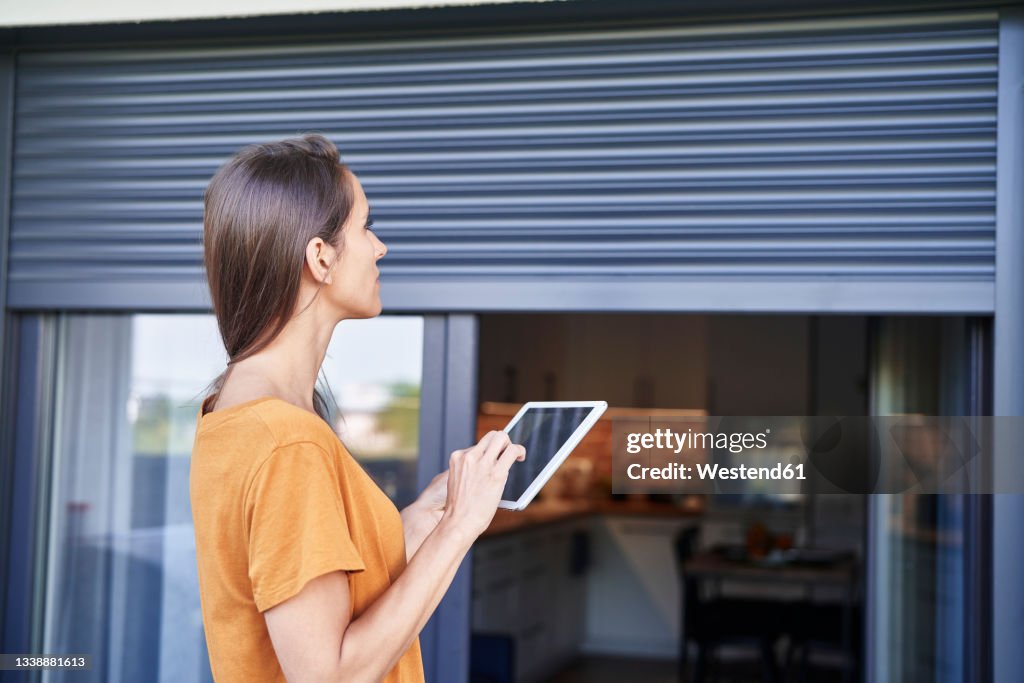 Woman controlling blinds through digital tablet