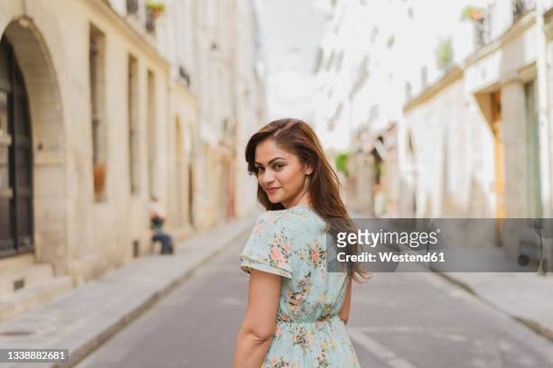 smiling beautiful woman standing on street - brunette woman back stockfoto's en -beelden