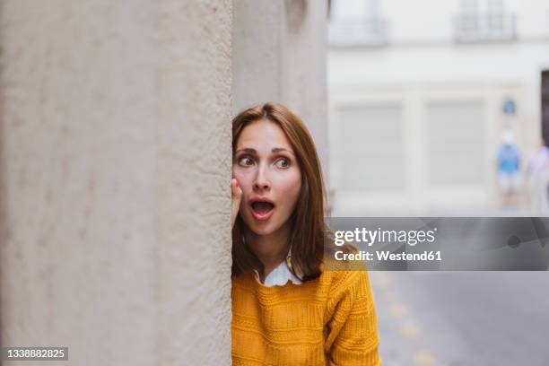 shocked young woman looking away while standing by wall - incidental people stock pictures, royalty-free photos & images