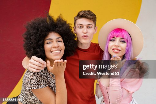Man puckering while female friends blowing kisses Man puckering while female friends blowing kisses