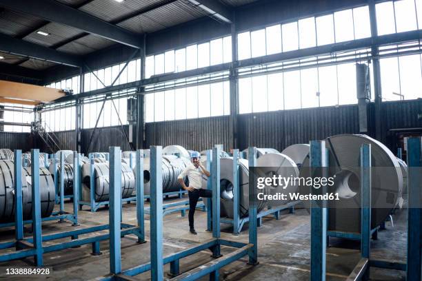 male engineer talking on mobile phone while standing at steel mill - roll call stock pictures, royalty-free photos & images