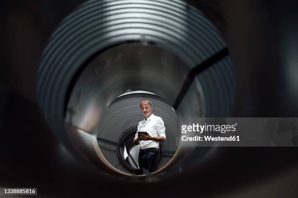 businessman with digital tablet seen through rolled up metal sheet - focus on background stock pictures, royalty-free photos & images