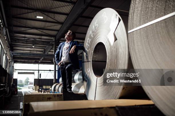 thoughtful businessman standing at steel sheet warehouse - blech stock-fotos und bilder