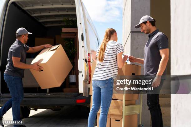 woman signing on document while receiving packages from delivery males - male hair removal stockfoto's en -beelden