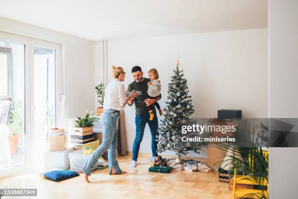 moving in: mother giving christmas present to her cute daughter - homeowners decorate their houses for christmas stockfoto's en -beelden