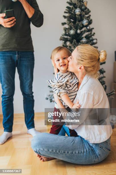 mother kissing her cute daughter at home - homeowners decorate their houses for christmas stockfoto's en -beelden