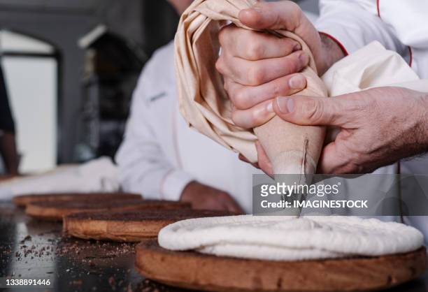 pastry chef filling sponge cake with cream from the piping bag - pâtissier photos et images de collection