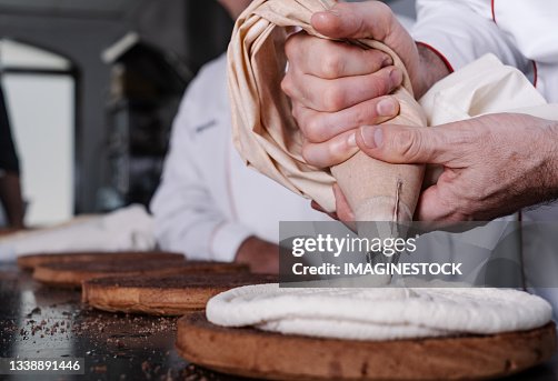 Pastry chef filling sponge cake with cream from the piping bag Pastry chef filling sponge cake with cream from the piping bag