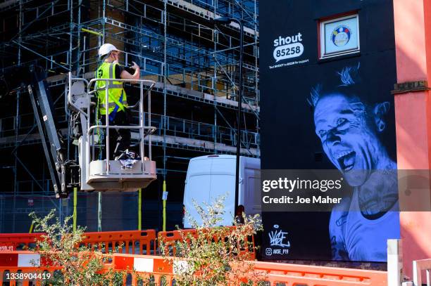 Street artist Akse P19 takes photos of his finished work during the unveiling of The Prodigy's Keith Flint mural ahead of World Suicide Prevention...