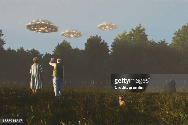 senior couple waving at flying ufos - flying saucer stock pictures, royalty-free photos & images