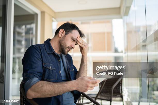 uomo preoccupato che usa lo smartphone dal balcone dell'appartamento - male surprised foto e immagini stock