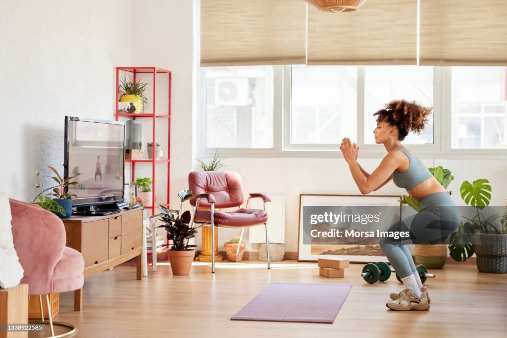 Young Woman Practicing Squats In Living Room