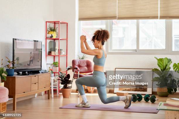 woman practicing lunges at home - tv room side imagens e fotografias de stock