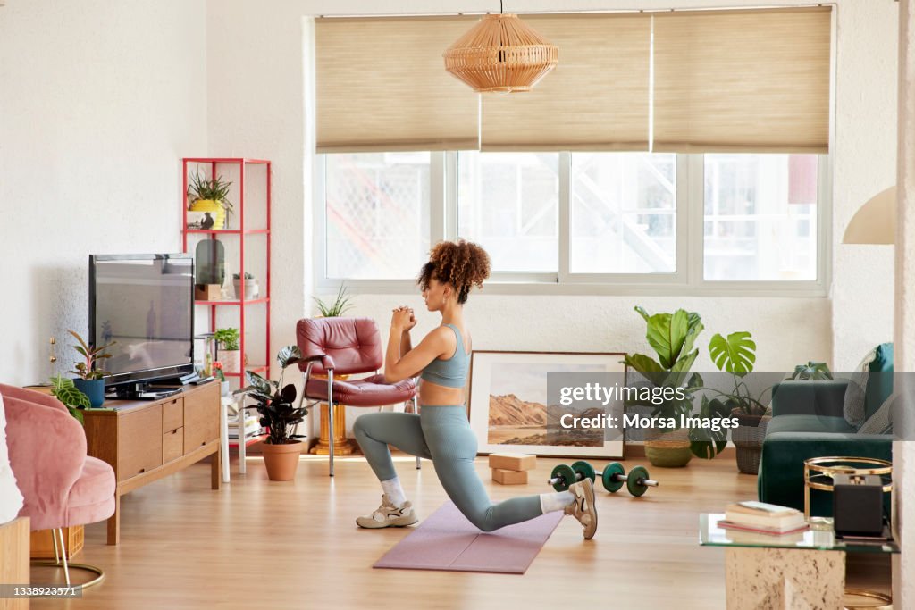Young Woman Doing Lunges In Living Room