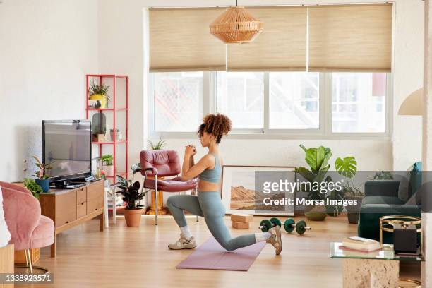 young woman doing lunges in living room - lunge imagens e fotografias de stock