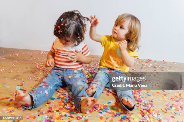childrens sitting on the floor playing with confetti in a playroom - sparkle children stock pictures, royalty-free photos & images