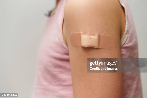 close up of band aid, on the arm of a caucasian girl after giving her the vaccine - child arms up stock pictures, royalty-free photos & images