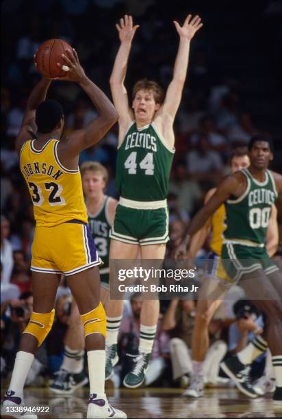 Los Angeles Lakers Magic Johnson looks to pass the ball around the raised-arms of Boston Celtics Danny Ainge during 1985 NBA Finals between Los...