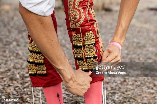 detail view of an unrecognizable young adult bullfighter putting on his traditional red and gold costume - bullfighter stock-fotos und bilder