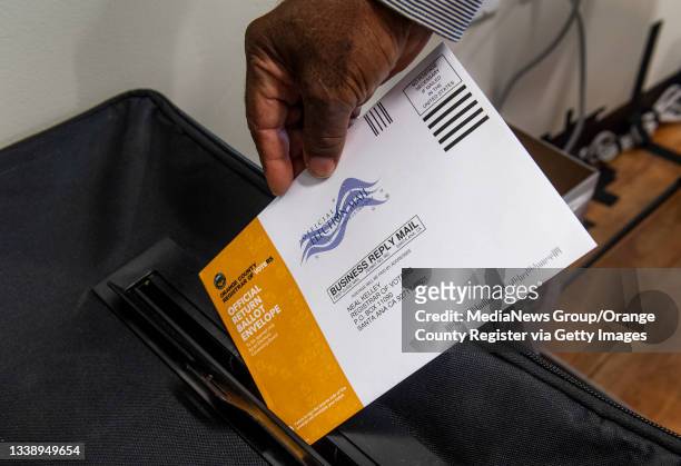 Poll worker puts a mail-in ballot in a security box in the recall election of Gov. Gavin Newsom at a center in San Clemente, CA on Tuesday, September...