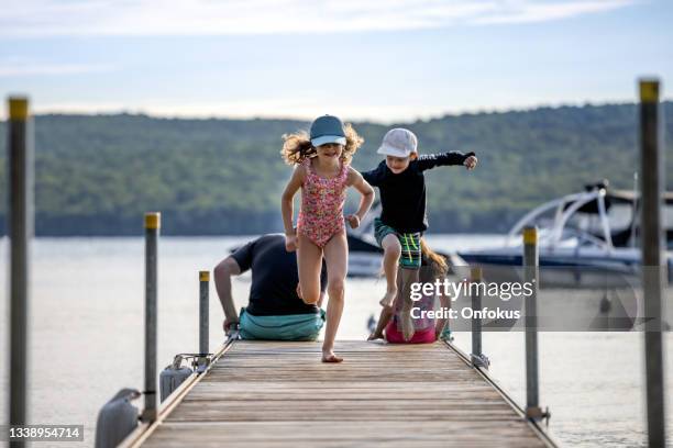 padre con tre bambini seduto sul molo del lago durante le vacanze estive, quebec, canada - molo foto e immagini stock