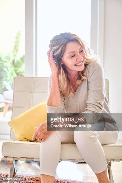 bella donna caucasica seduta sul divano che si rilassa a casa. bel sorriso. - older woman happy smile foto e immagini stock