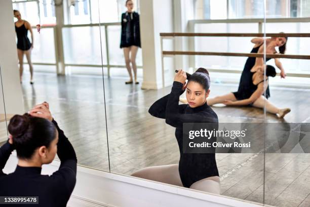 young woman doing her hair in a ballet studio - balletttänzer stock-fotos und bilder