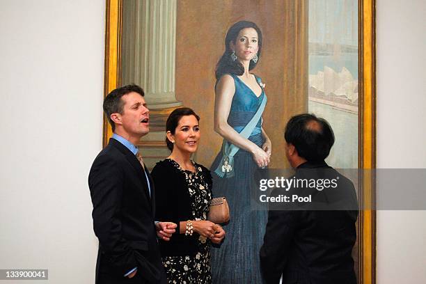 Princess Mary of Denmark and Prince Frederik of Denmark talk to artist Jiawei Shen while standing in front of a painting of Princess Mary at the...