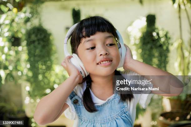 happy asian child girl listen the music song from wireless headphone from mp3 player technology. relaxation and music lover concept. - unterhaltungsberuf stock-fotos und bilder