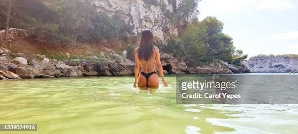 rear image of young woman in bikini walking into the mediterranean sea in minorca,spain - islas baleares fotografías e imágenes de stock